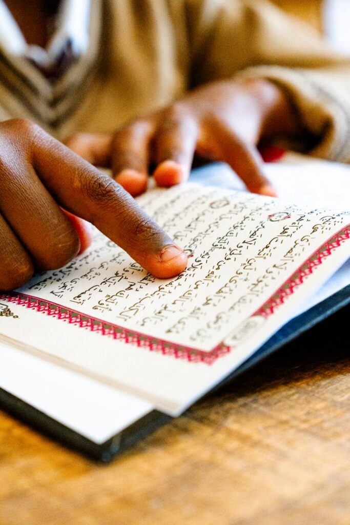 Mastering the First Impression: Your intriguing post title goes here Close-up of a child's hand pointing while reading the Quran indoors.